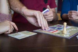 Een groep mensen die een bordspel spelen en tegelijkertijd gezonde relaties tussen het schoolpersoneel bevorderen door seksueel gepast gedrag te bevorderen. School en Veiligheid